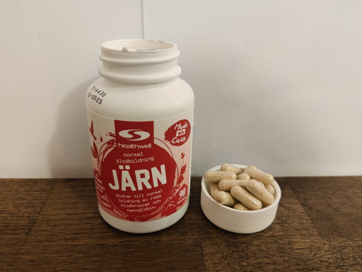 Healthwell Järn med kapslar intill burken på träyta, fotograferat av oss