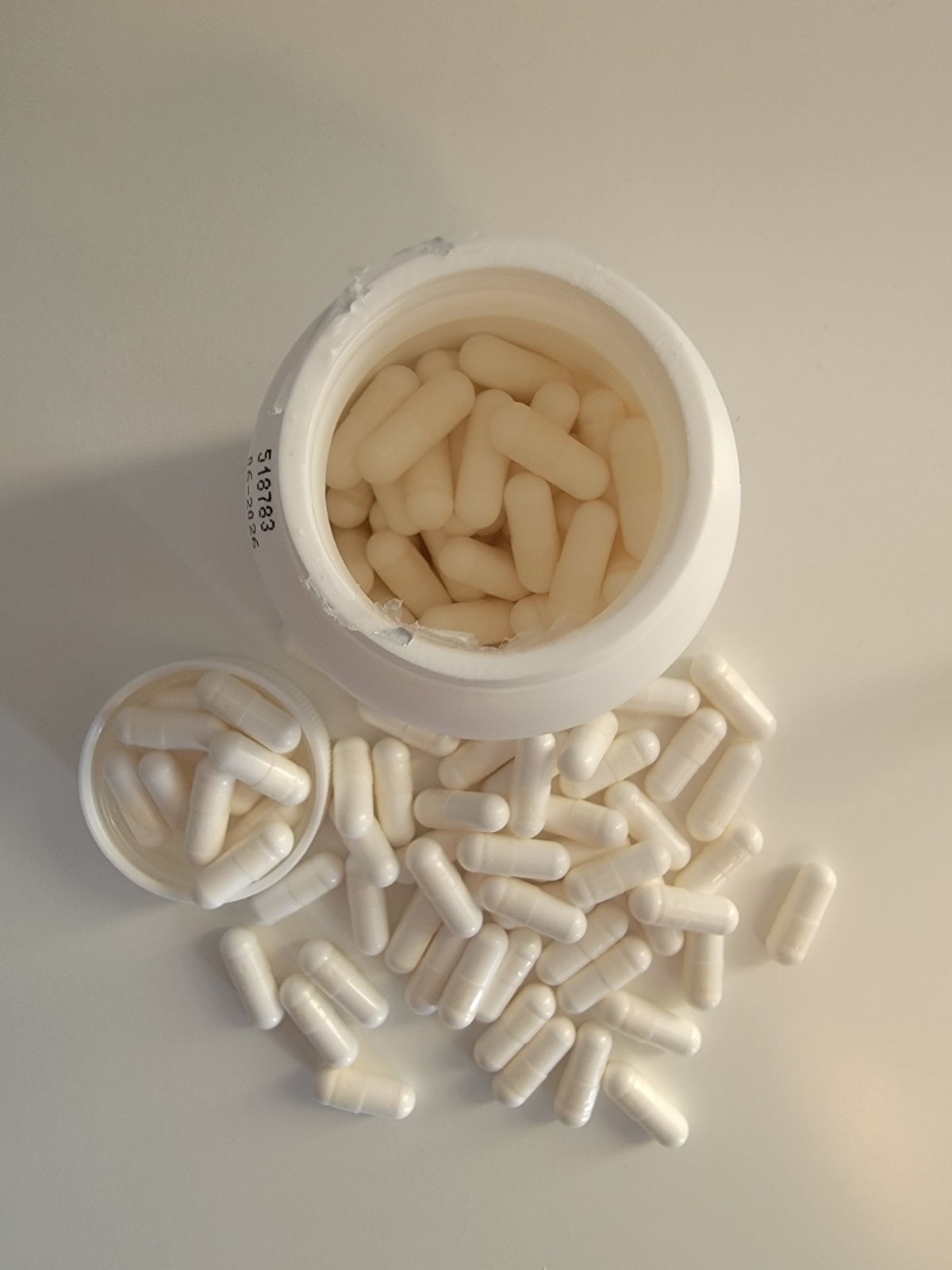 Vy uppifrån på öppnad burk med kapslar runtom, Healthwell Kalcium Magnesium, taget av oss