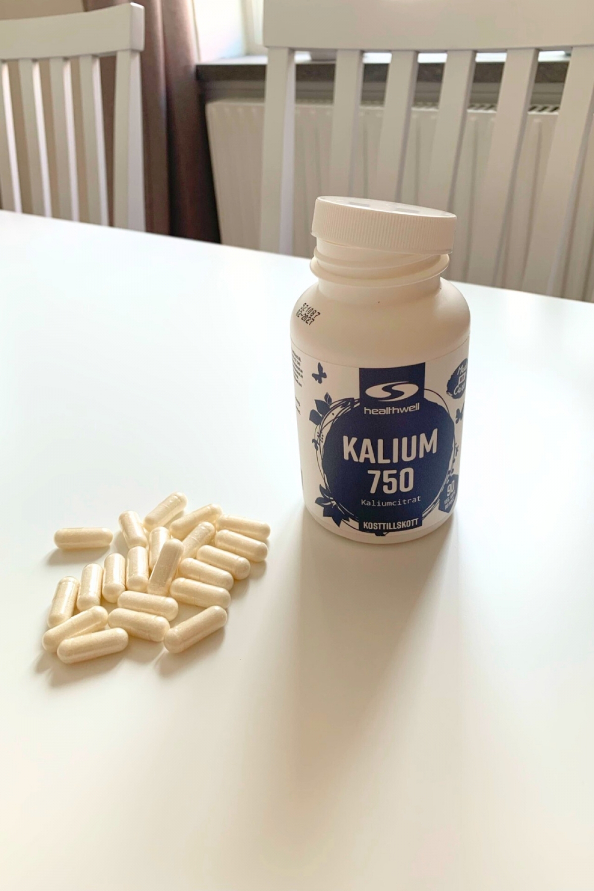 Kapslarna från Healthwell Kalium 750 utspridda bredvid burken, fotograferat av oss