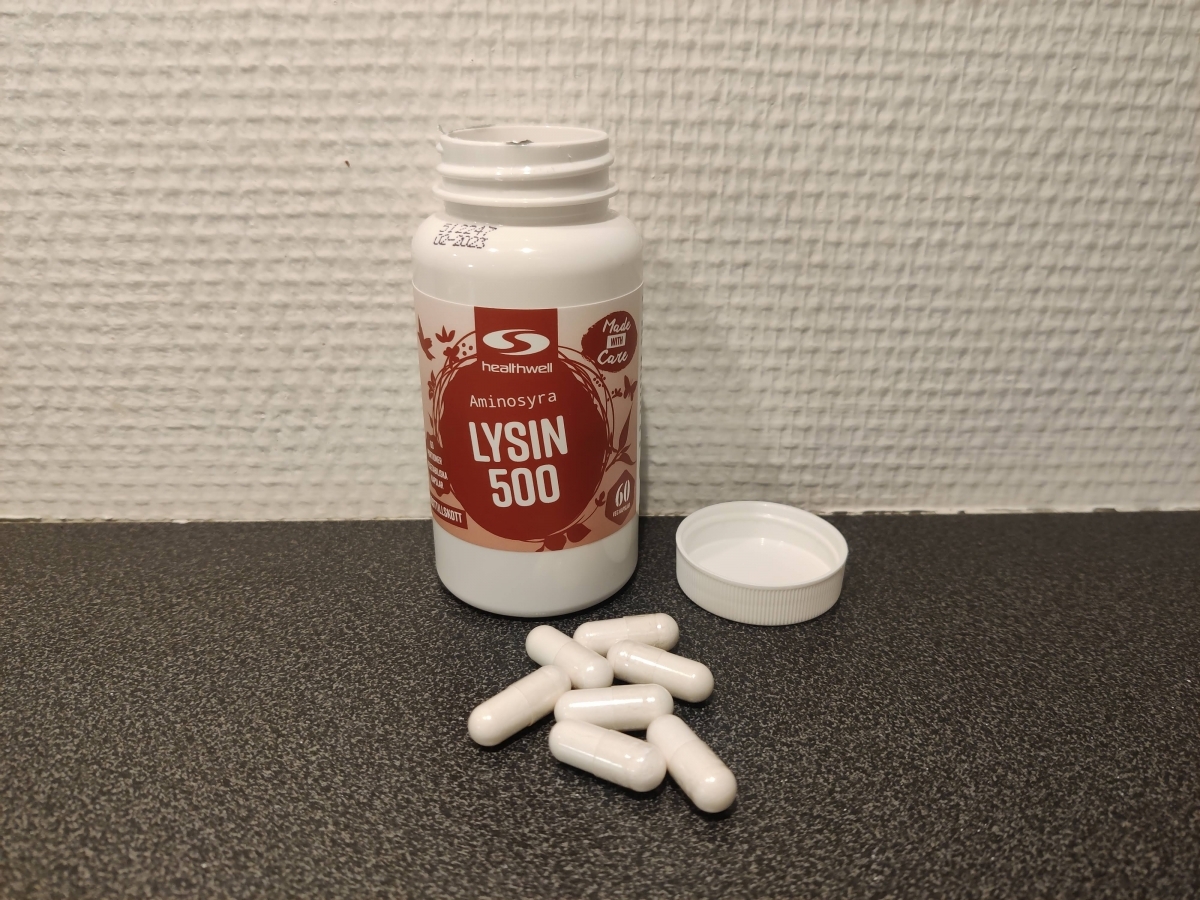 Öppnad burk Healthwell Lysin 500 med kapslar på bänken, egen testbild