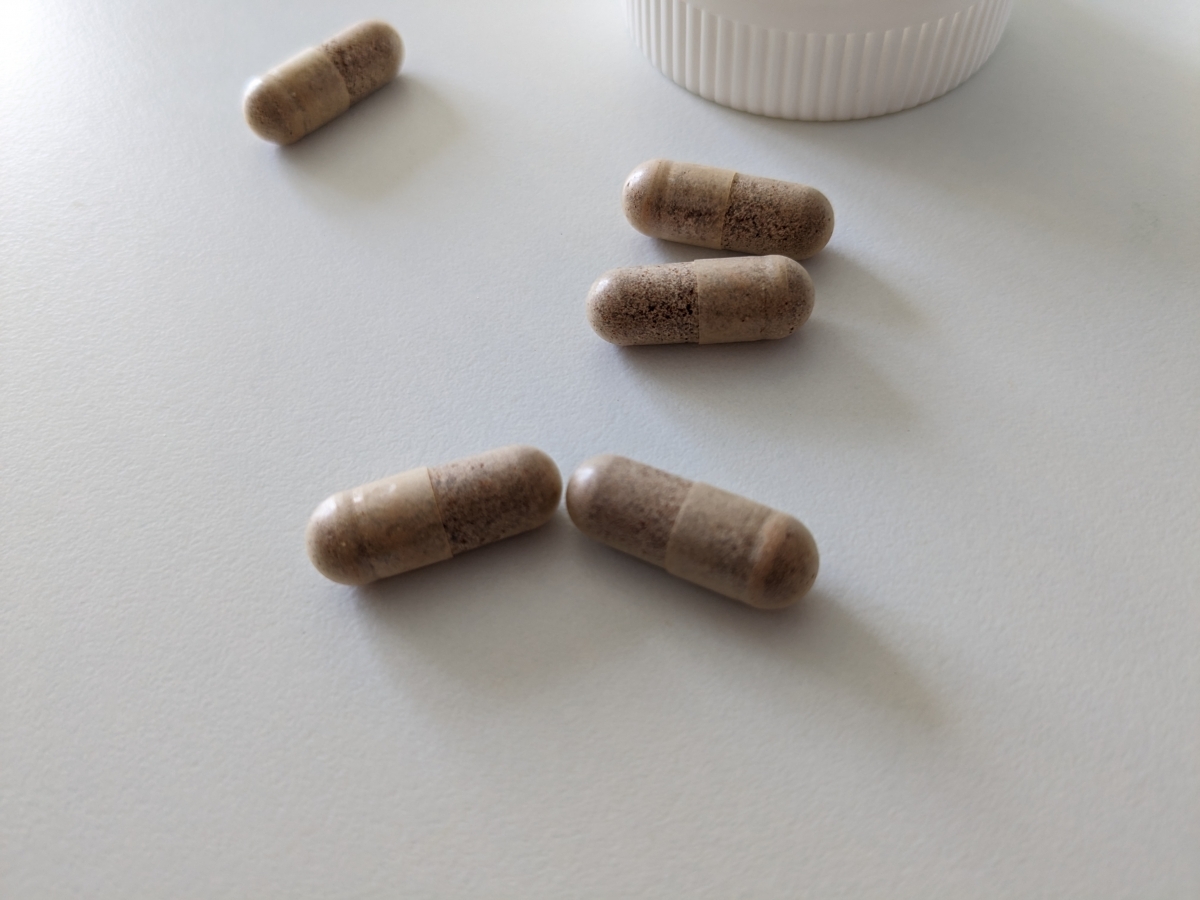 Närbild på Healthwell Multivitamin Man-kapslar tagna av oss; transparenta höljen som visar det finmalda innehållet