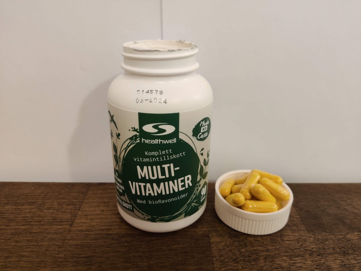 Närbild på Healthwell MultiVitaminer med flera kapslar bredvid taget av oss