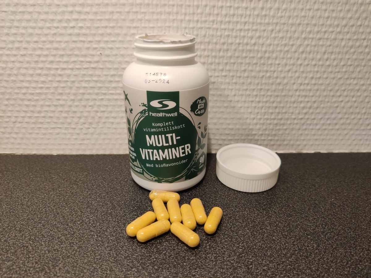 Öppnad burk Healthwell MultiVitaminer med kapslar på bänken foto taget av oss