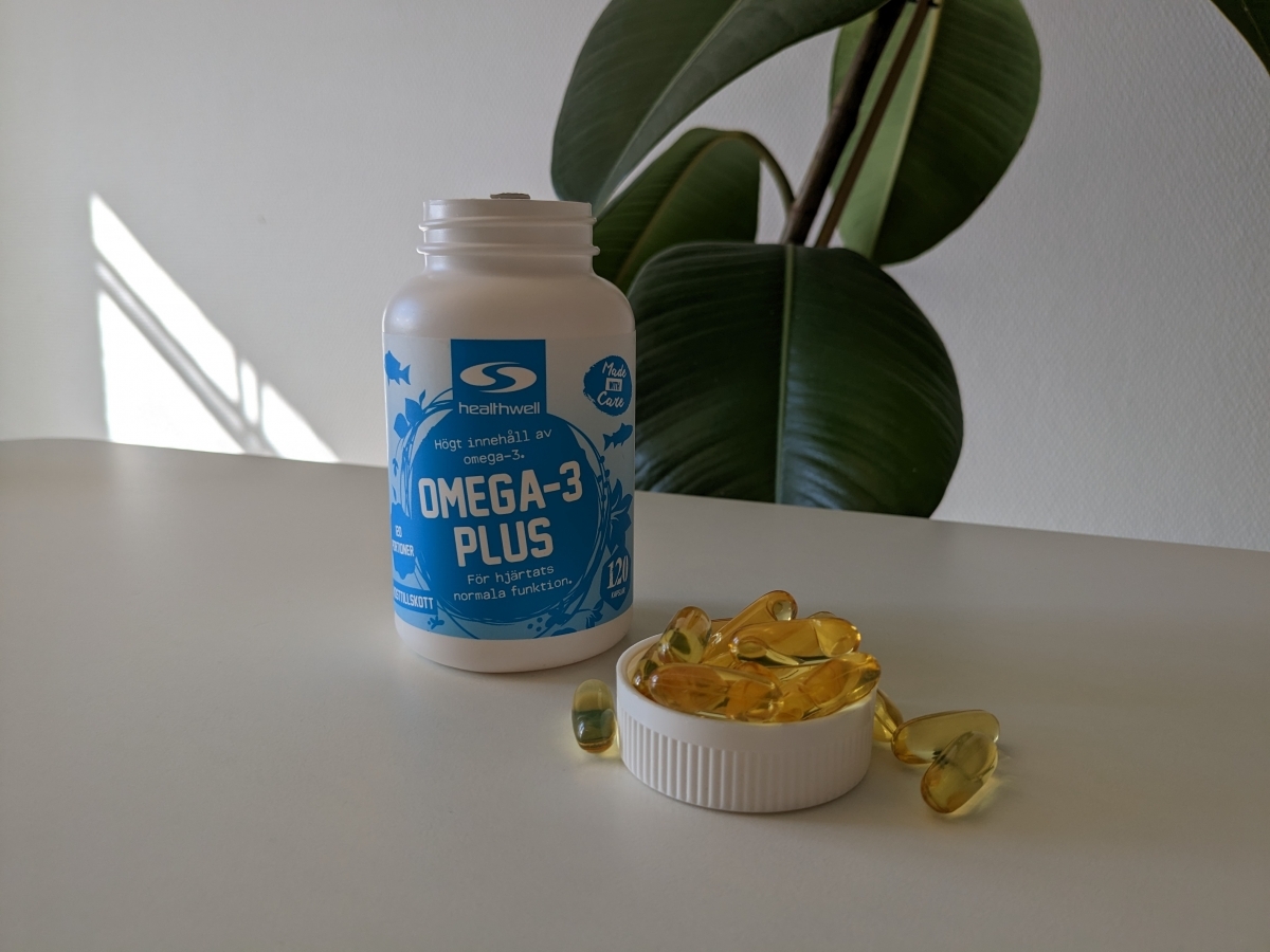 Healthwell Omega-3 Plus i dagsljus med kapslar på bordet, foto taget av oss under testet