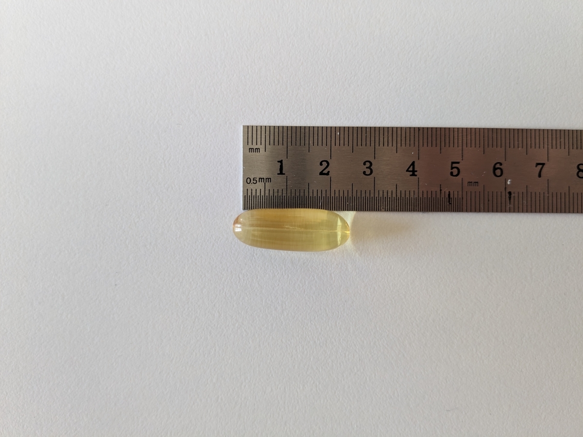 Kapsel från Healthwell Omega-3 Plus bredvid linjal cirka 23 mm, fotad under vårt test