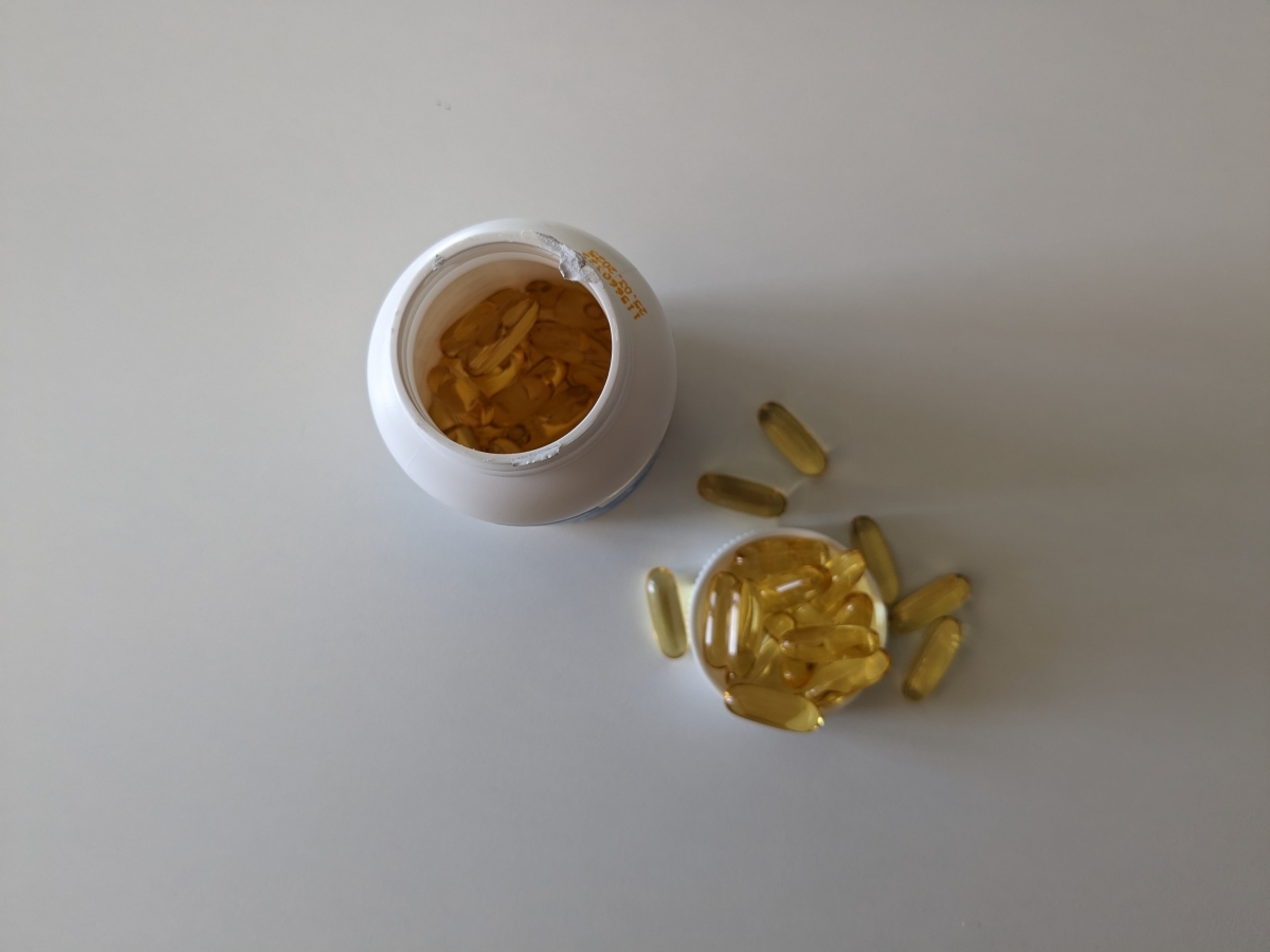 Öppnad burk av Healthwell Omega-3 Plus ovanifrån med några kapslar utspridda, eget testfoto