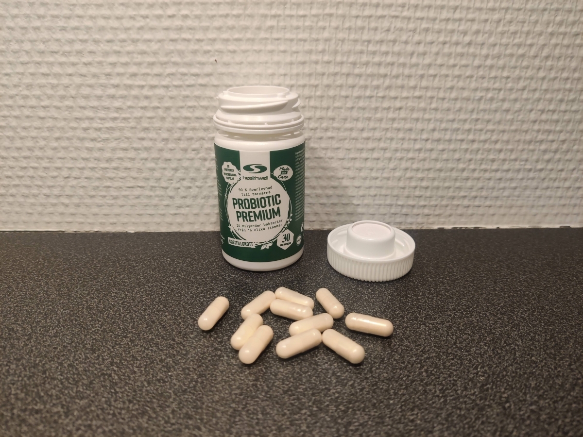 Healthwell Probiotic Premium burk och kapslar på bänkskiva, foto taget av oss under testet
