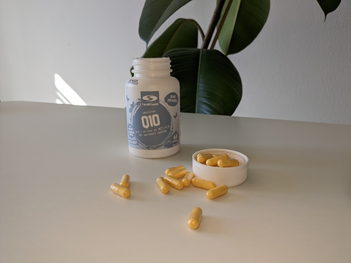 Healthwell Q10 50 fotograferad av oss under testet – öppen burk och kapslar i mjukt dagsljus
