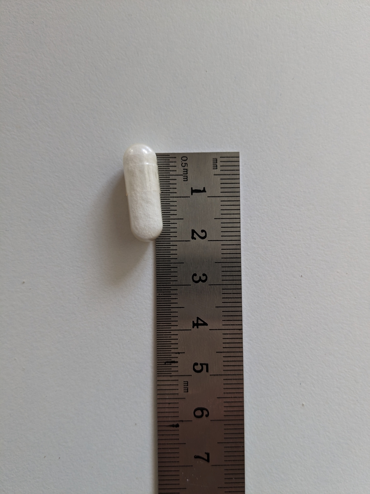 Healthwell Selen kapsel bredvid linjal visar kompakt storlek cirka 2 cm