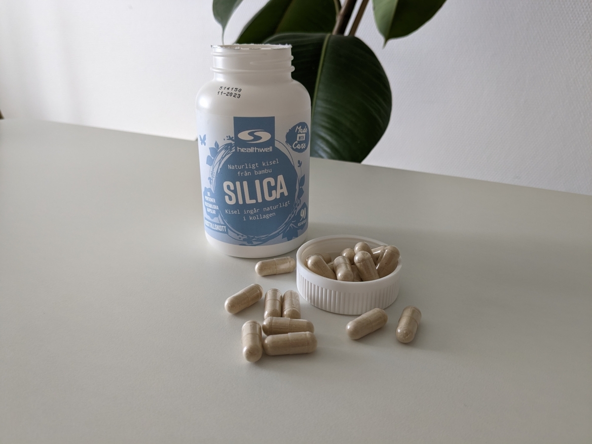 Öppen burk Healthwell Silica och kapslar på bordet, vårt testfoto