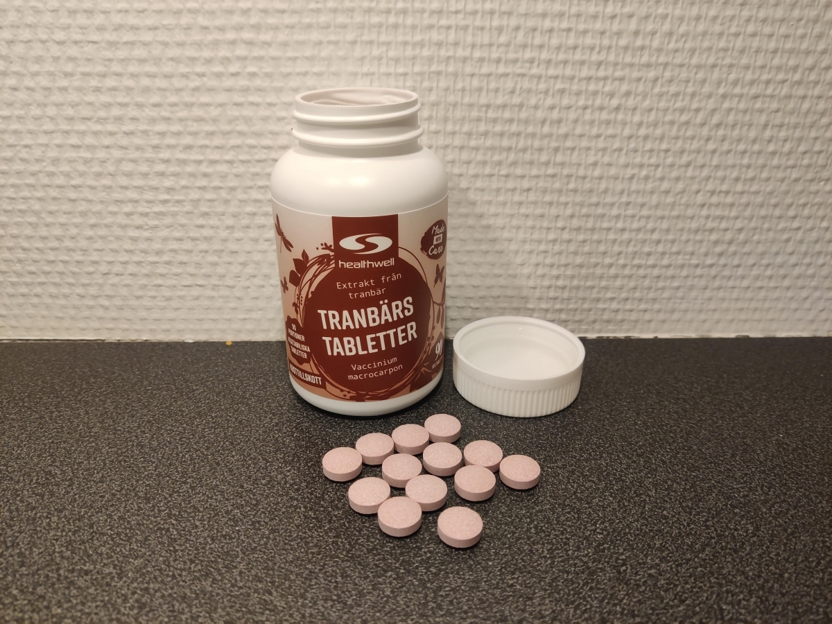 Öppen burk med rosa tranbärstabletter på bänkskiva, foto från vårt test