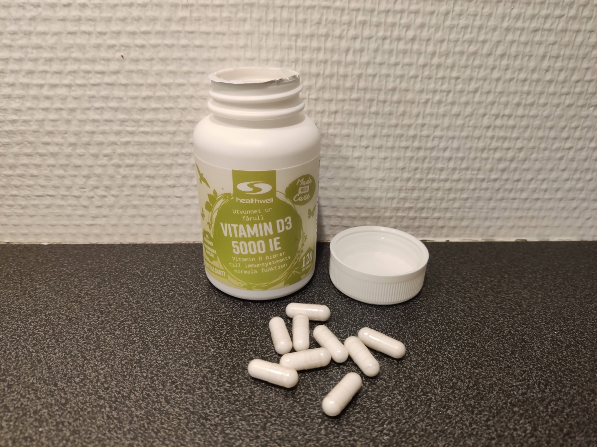 Healthwell Vitamin D3 5000 IE, öppnad burk med kapslar på mörk bänkskiva, foto från vårt test