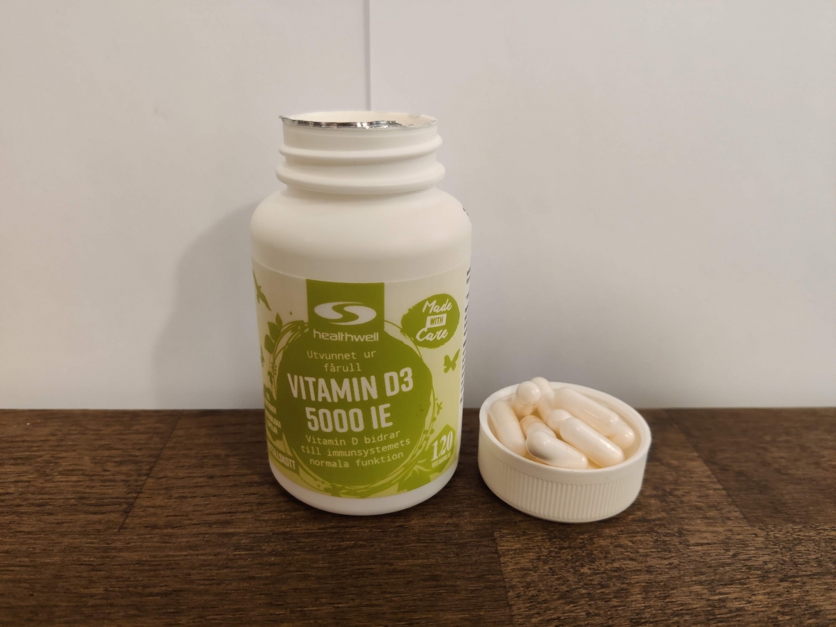 Healthwell Vitamin D3 5000 IE på träbord, vårt eget foto