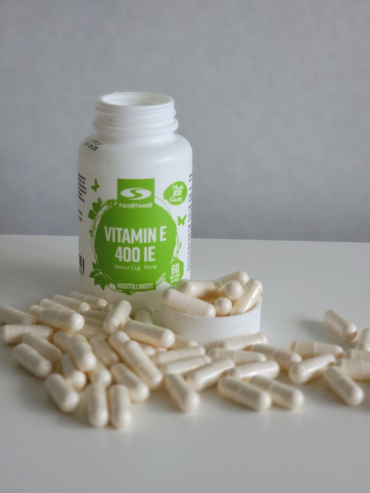 Vår egen bild av Healthwell Vitamin E 400 IE med öppnad burk och utspridda kapslar under testet