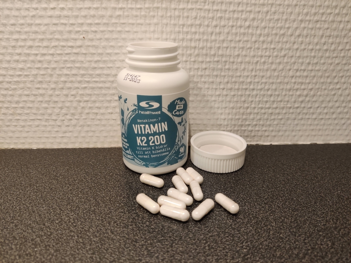 Healthwell Vitamin K2 200 µg, egen bild från testet – öppnad burk och kapslar på bänkskiva
