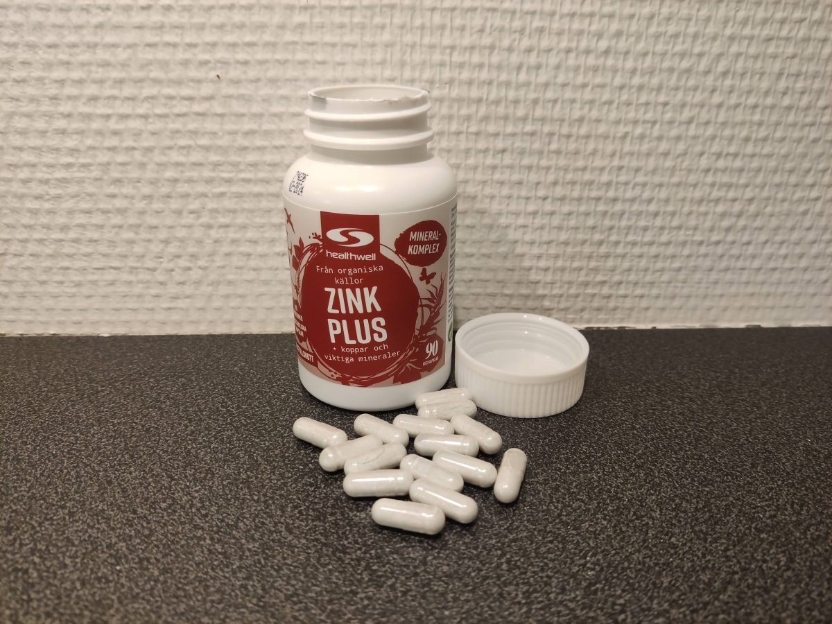 Healthwell Zink 25 Plus fotograferad av oss under testet, öppen burk med kapslar på mörk bänk