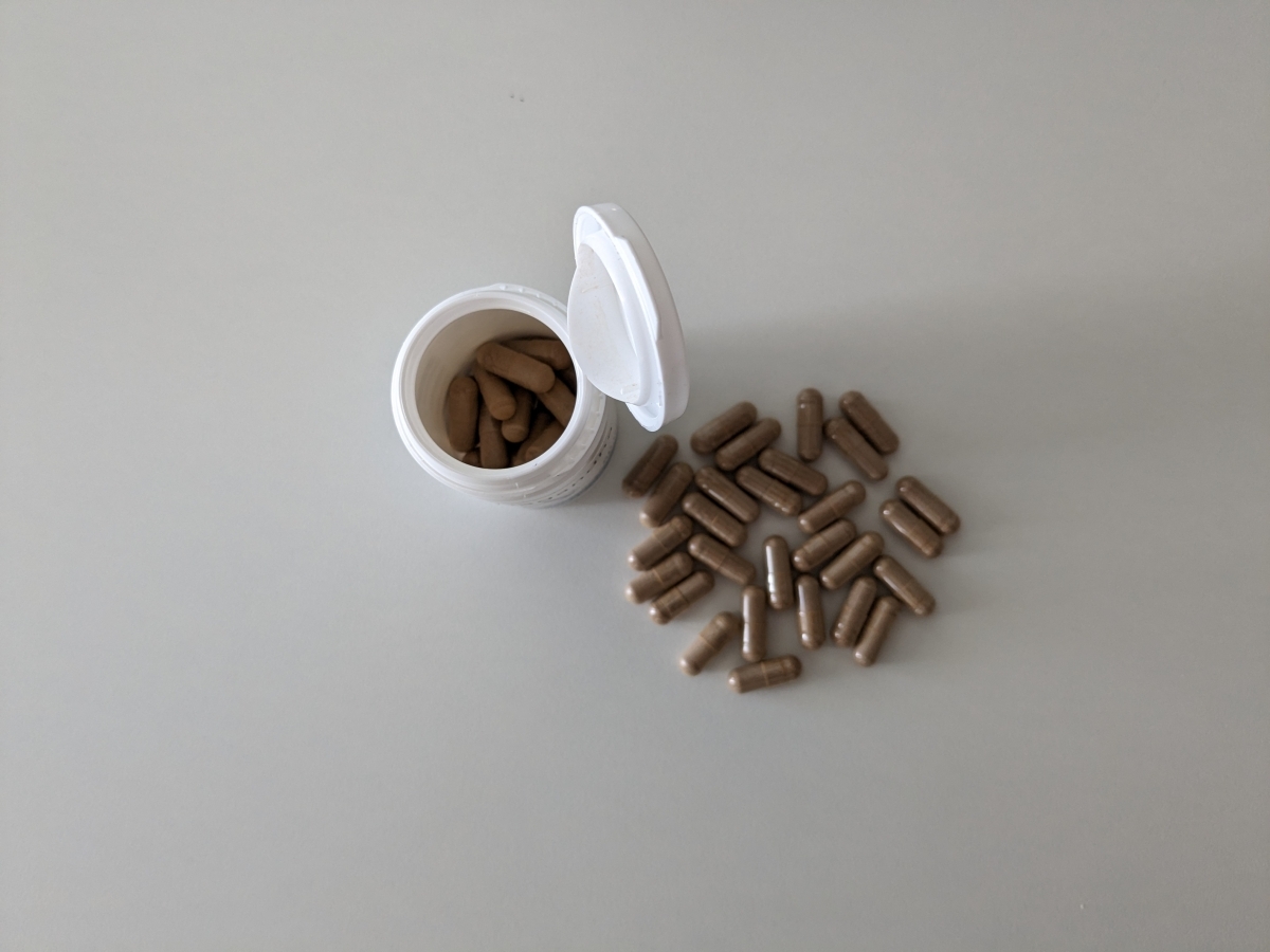 Öppen burk uppifrån med utspridda kapslar av Helhetshälsa Ashwagandha