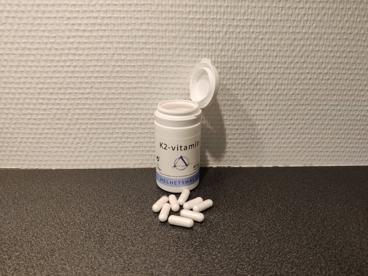 Helhetshälsa K2-Vitamin öppnad burk med kapslar på bänkskiva, fotad av oss under användning