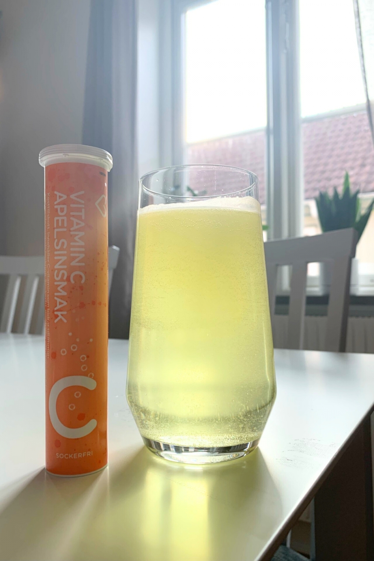 Upplöst C-vitamin i klart pärlande glas bredvid röret, fotograferat av oss