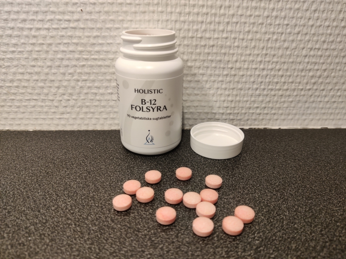 Holistic B12 Folsyra öppnad burk med rosa sugtabletter på bänkskiva foto av oss