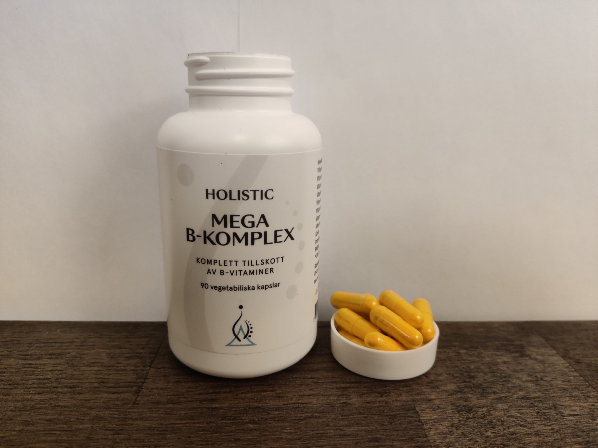 Holistic Mega B‑komplex på träbord med några kapslar bredvid – vårt foto