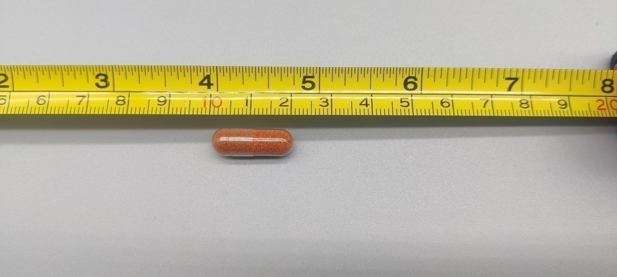 En Core Betakaroten-kapsel uppmätt mot måttband cirka 2 cm, vårt foto