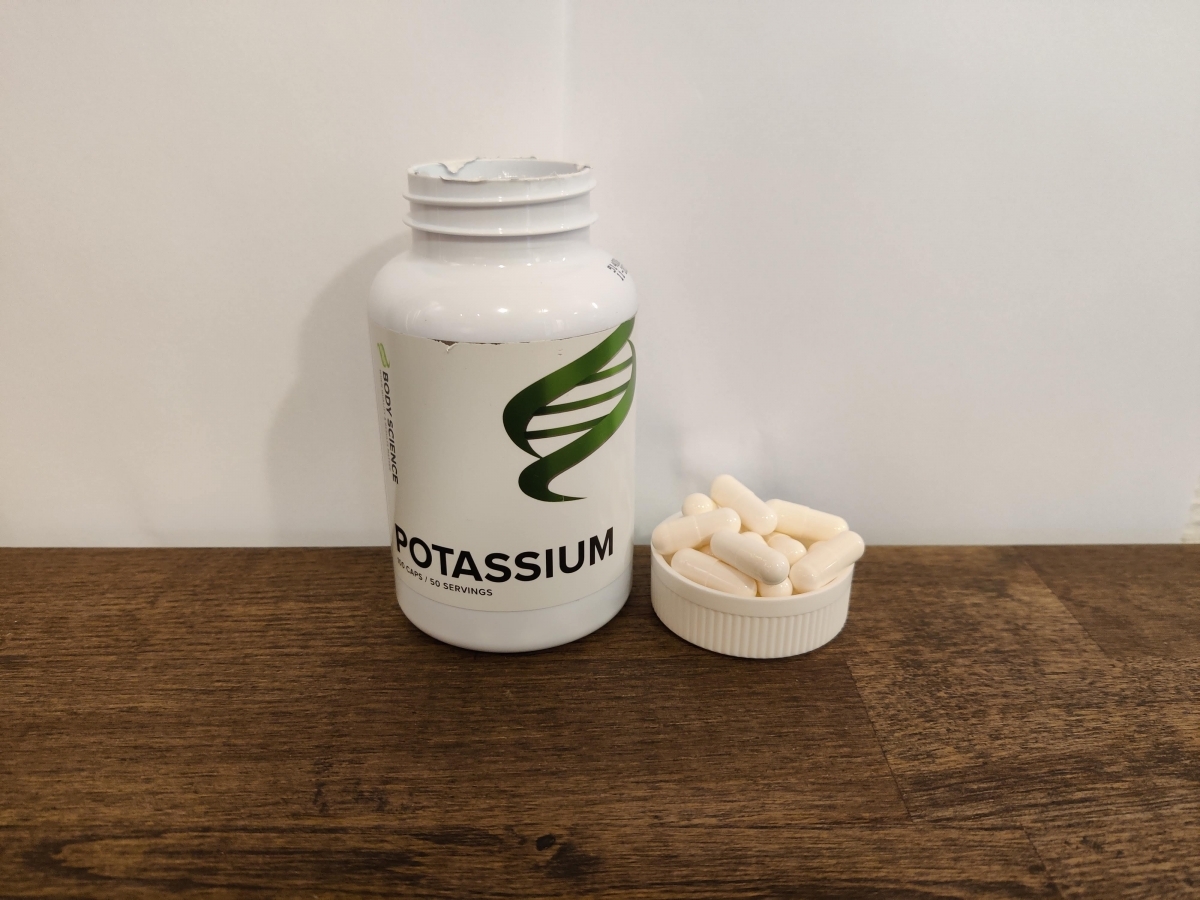 Kapslarna upplagda bredvid burken på träbord Body Science Kalium eget foto