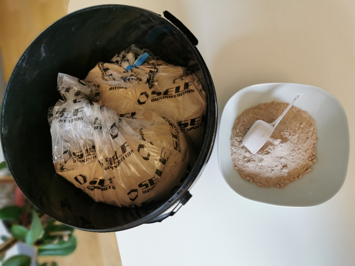 Öppnad hink med innerpåsar och upphälld portion pulver i skål med skopa, taget i vårt kök