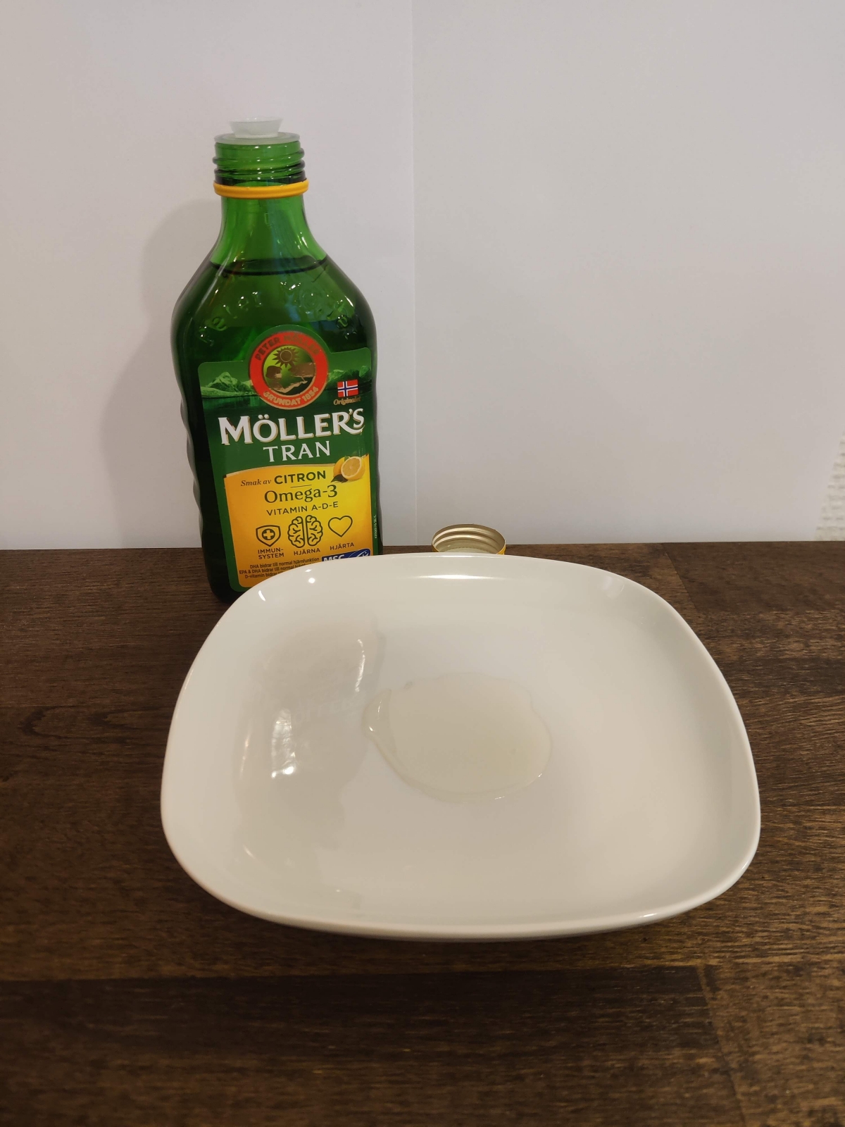 Närbild av Möllers Tran upphälld på vit tallrik bredvid flaskan från vårt eget test