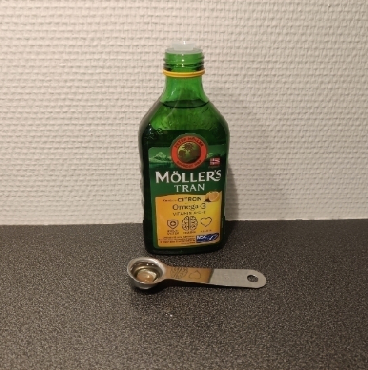 Möllers Tran citron i glasflaska med måttsked foto taget av oss under testet