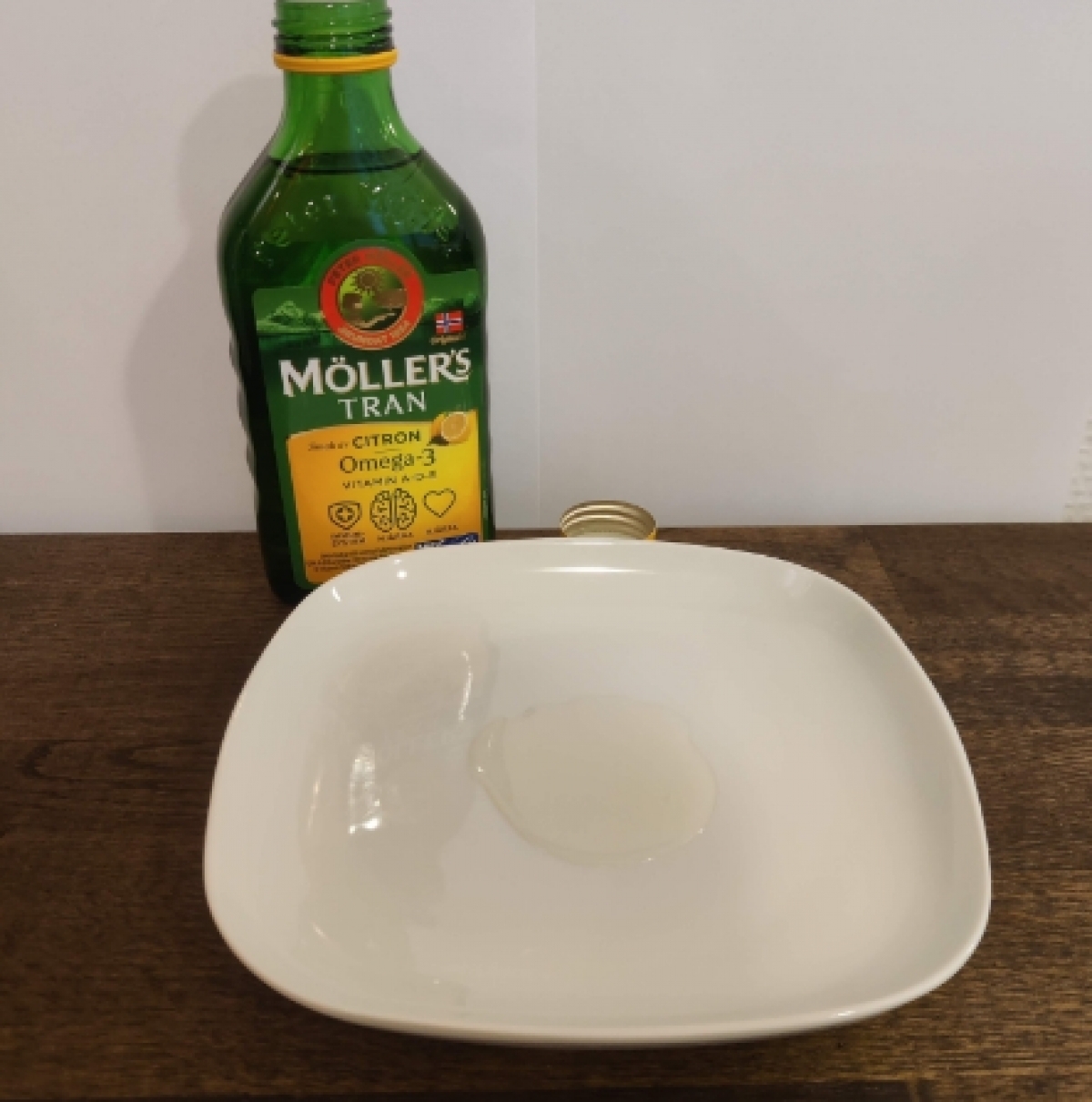 Möllers Tran upphälld på vitt fat ljus och klar olja