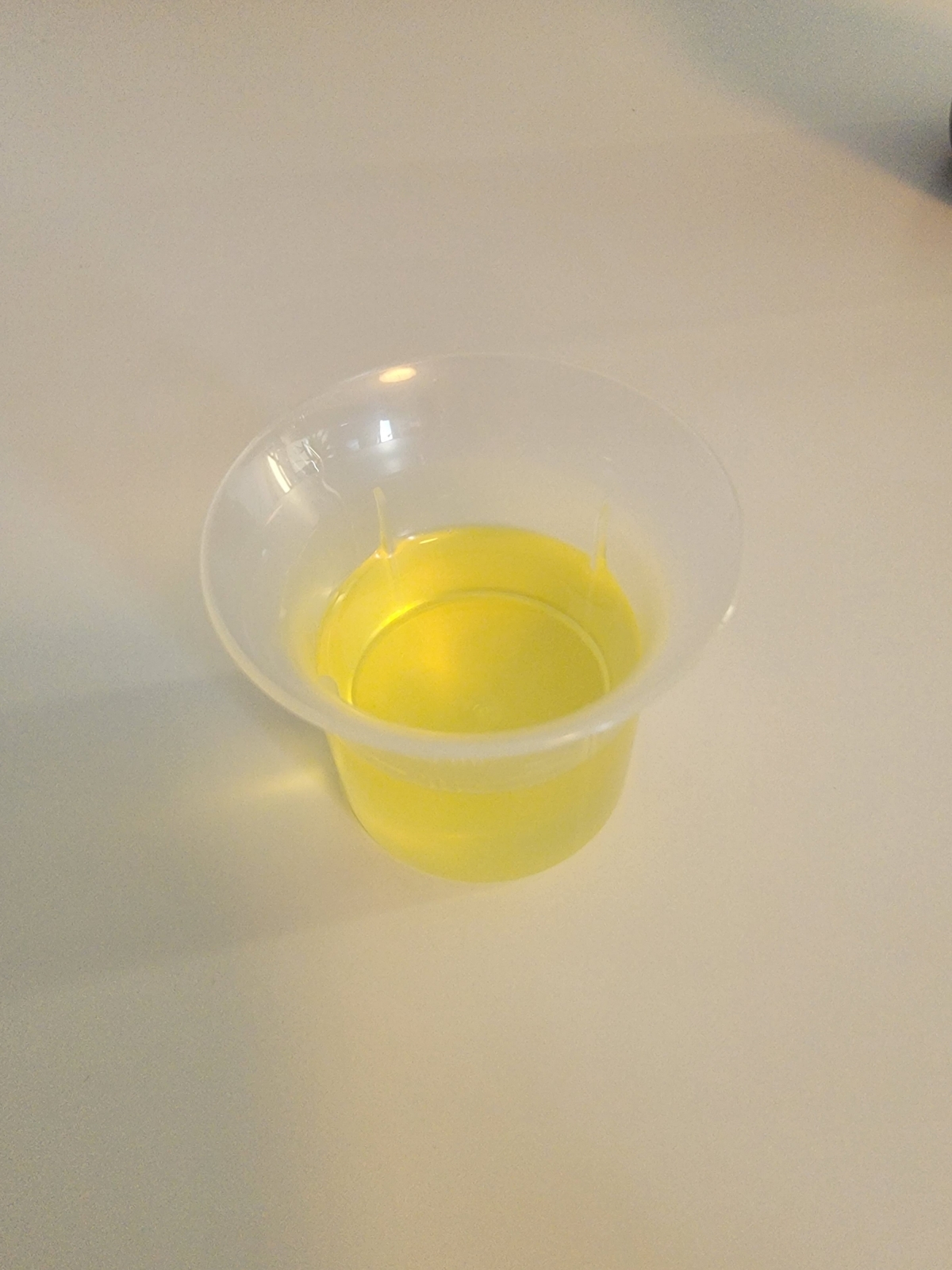 Närbild av den tunna, ljusgula oljan i provkopp tagen av oss