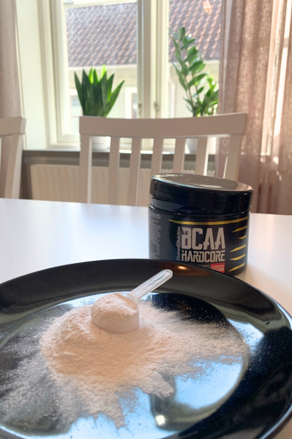Närbild på skopa pulver i dagsljus med BCAA-burk i bakgrunden, vår testbild