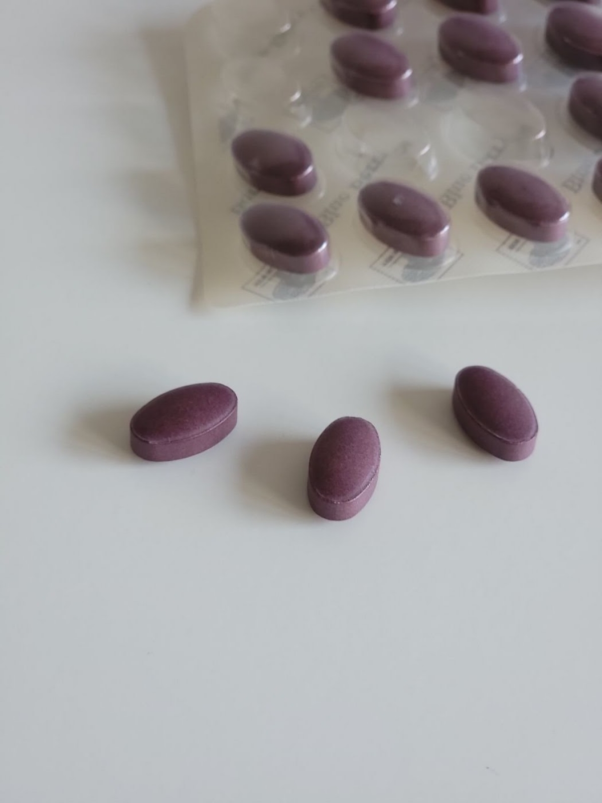 Närbild på matta lila tabletter av Blue Berry Plus i jämn oval form, foto av oss