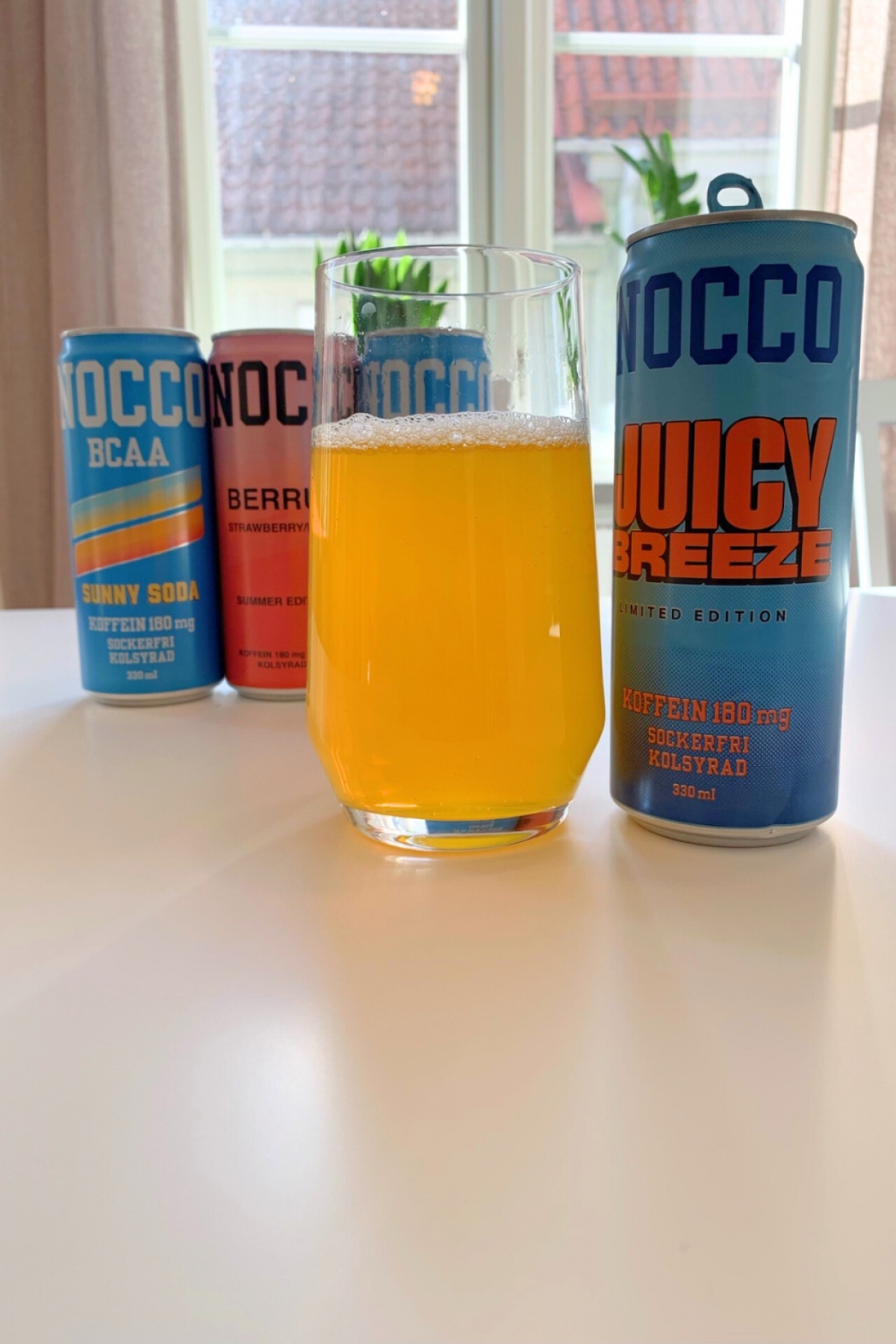 Juicy Breeze upphälld i glas framför övriga NOCCO-burkar från vårt test