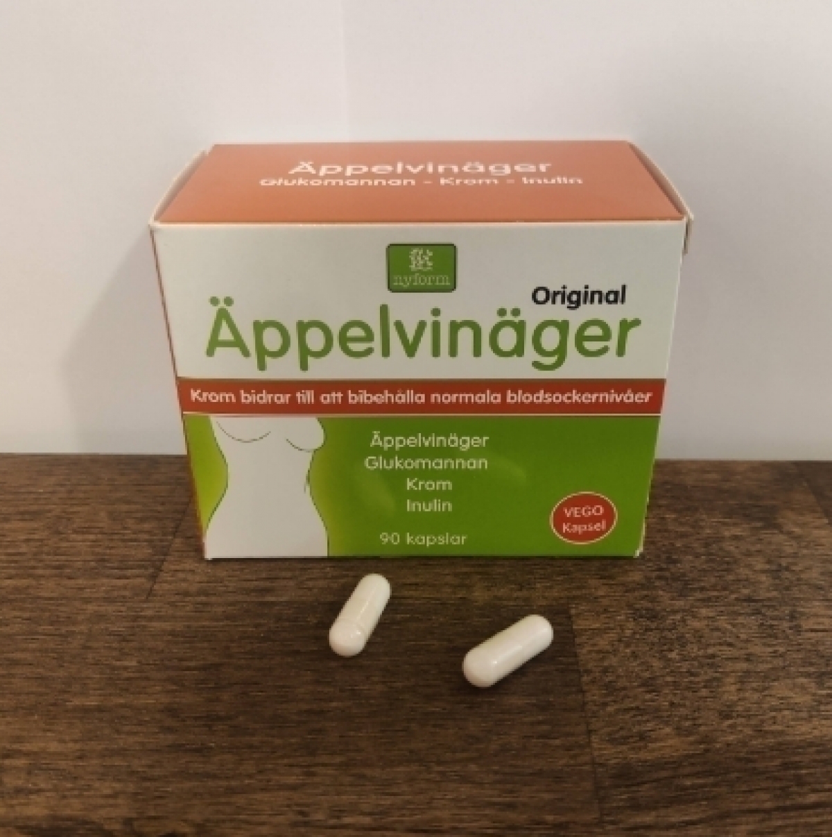 Två kapslar framför kartongen på träbord, foto taget av oss under testet