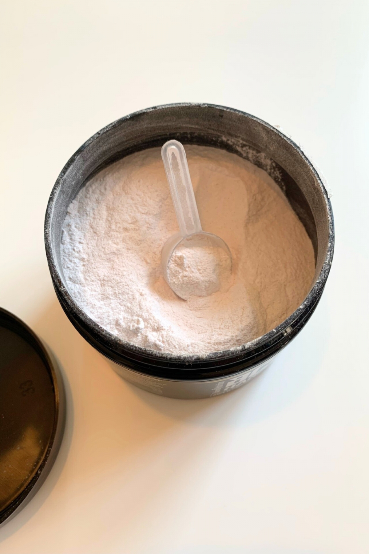 Öppen burk med vitrosa pulver och skopa av BCAA Hardcore, vår testbild