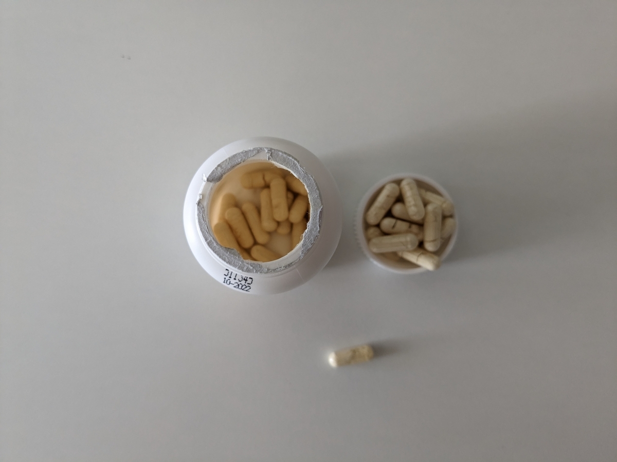 Ovanifrånbild tagen av oss av öppnad burk med foliesigill och kapslar bredvid