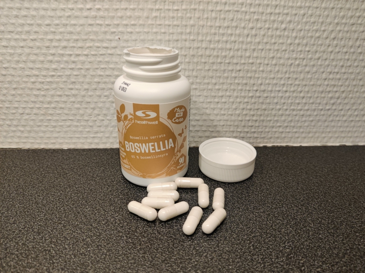 Öppnad burk och utspridda kapslar av Healthwell Boswellia i köksljus, foto taget av oss