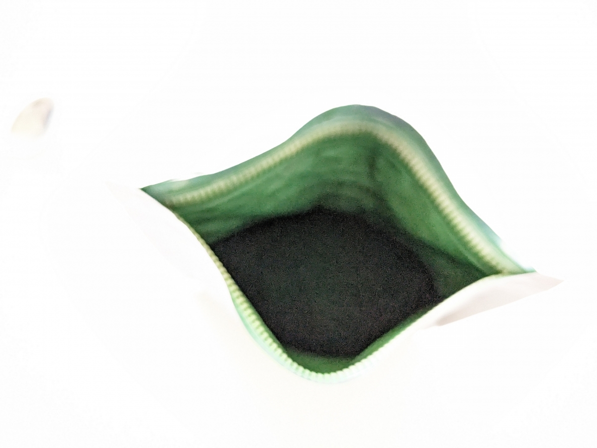 Öppnad påse med mörkgrönt spirulinapulver från Healthwell, fotad av oss under testet