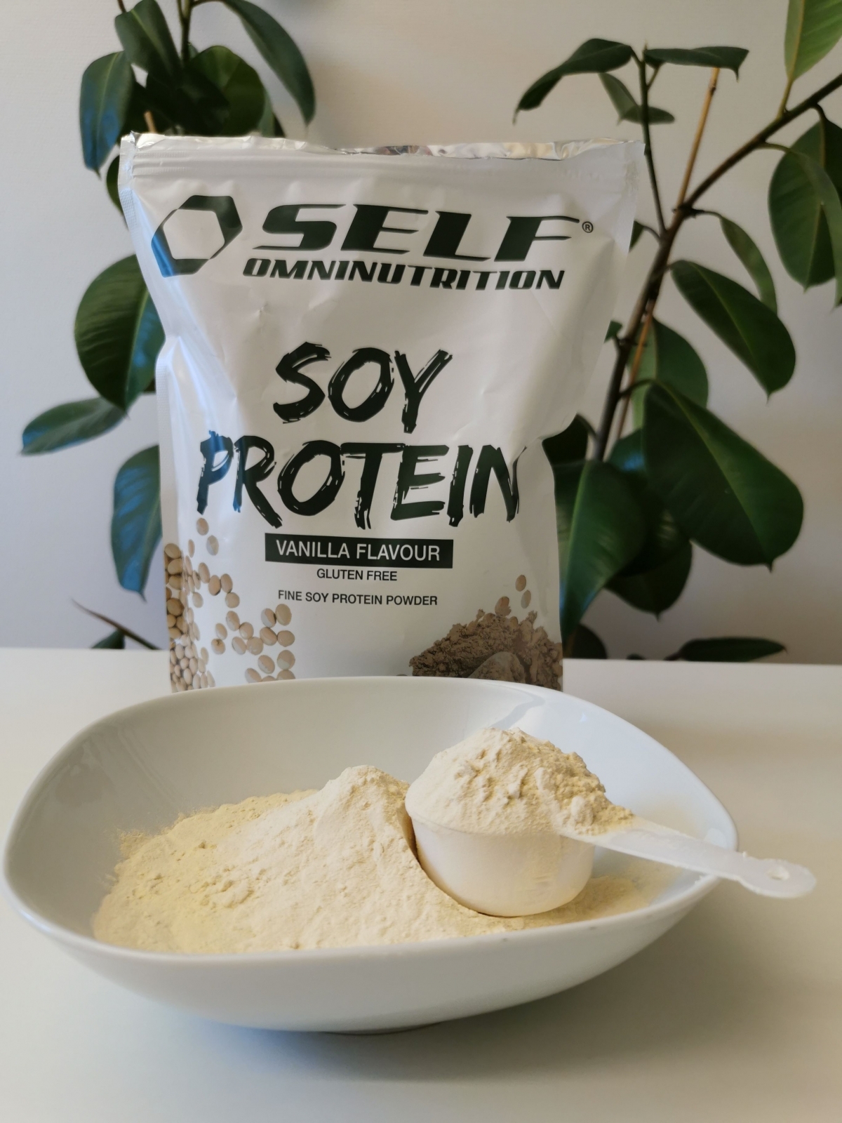 Finmalet <a href='https://www.kostnord.se/kosttillskott/sojaprotein'>sojaprotein</a> i skål med skopa framför förpackningen