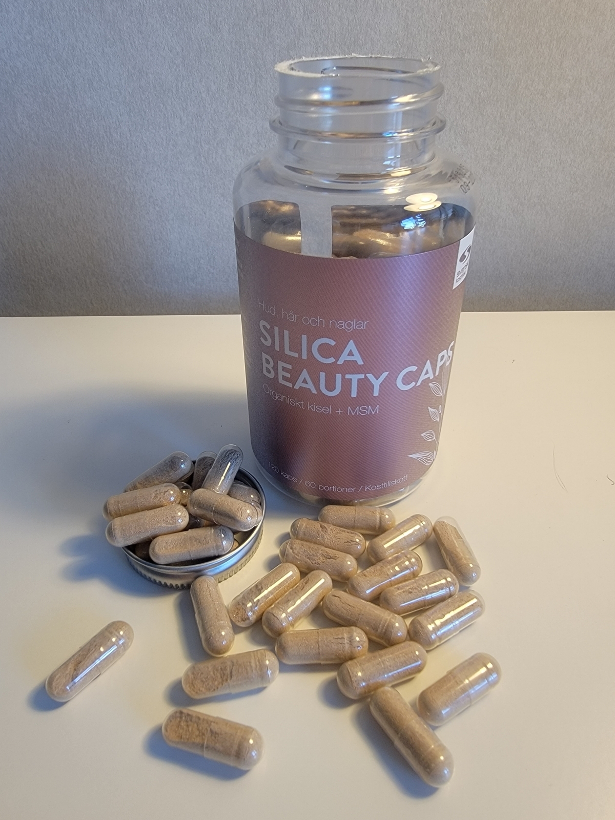 Framsida på Silica Beauty Caps med kapslar intill burken i naturligt ljus, foto av oss