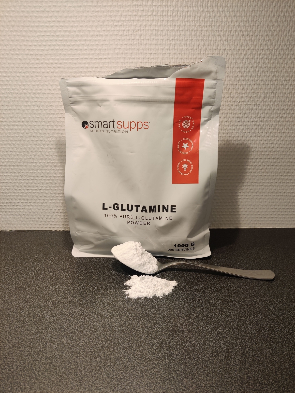 Sked med glutamin och lite spill på köksbänken framför påsen, vårt foto