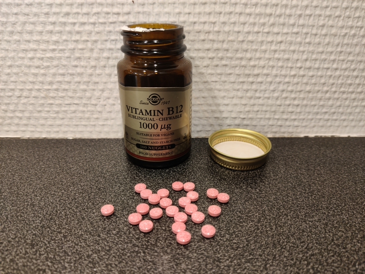 Solgar B12 tuggtabletter öppnad burk och utspridda rosa tabletter foto av oss