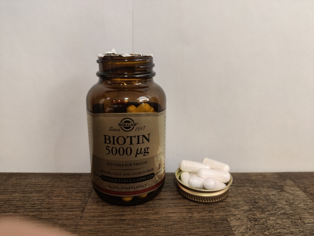 Solgar Biotin 5000 µg i glasburk på träbord med avtaget lock, eget foto