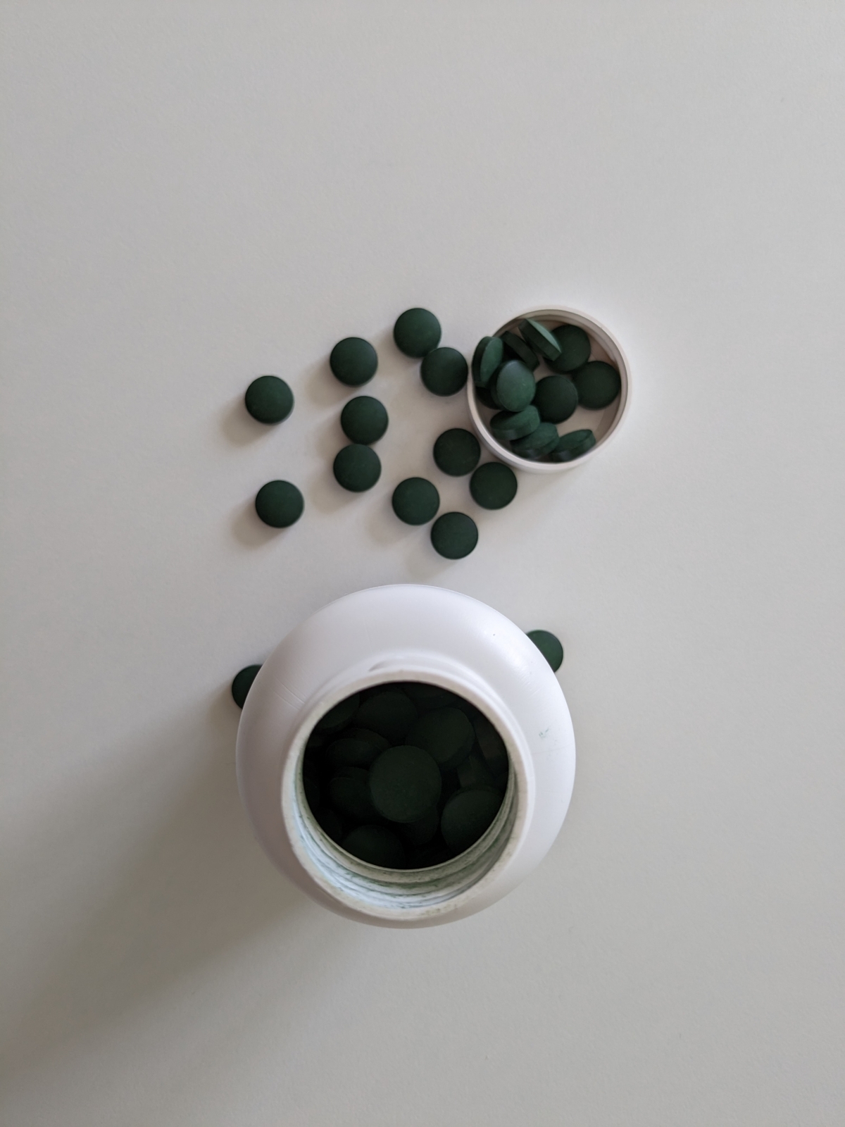 Spirulinatabletter uppifrån med öppnad flaska och lock, eget foto från testet