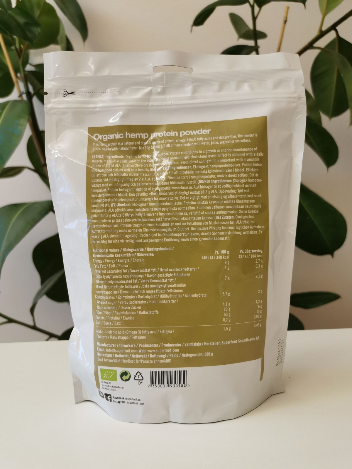 Superfruit Hampaprotein baksida mot ljus bakgrund med växt fotograferad av oss