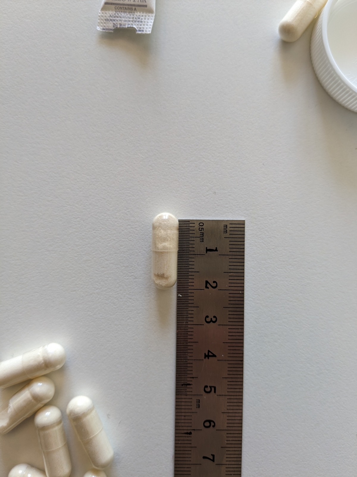 Kapsel från Thorne PharmaGABA-100 bredvid linjal cirka 2 cm, egen mätning