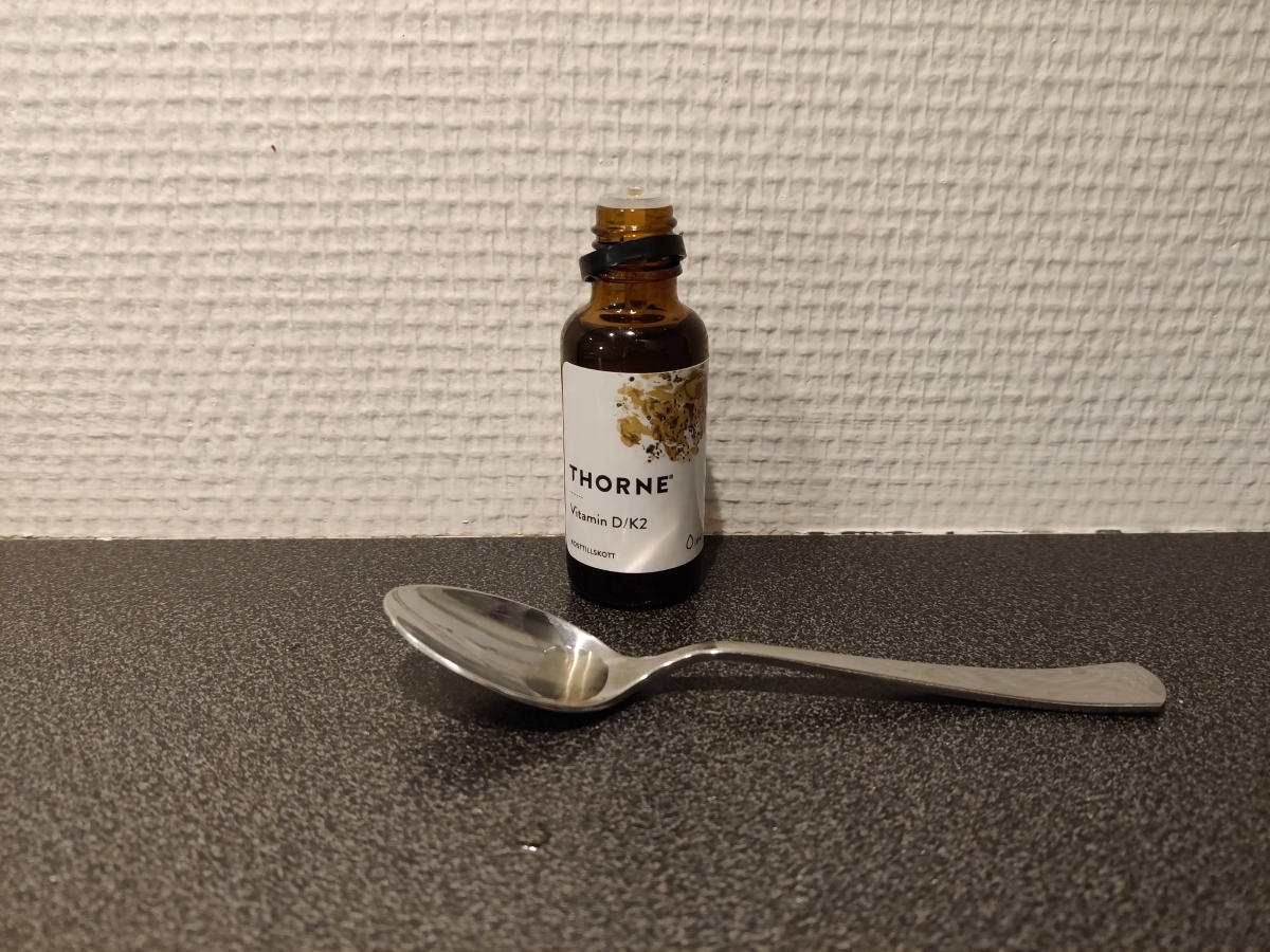 Thorne <a href='https://www.kostnord.se/kosttillskott/d-vitamin'>Vitamin D</a> K2 droppflaska med sked på bänk foto från vårt test