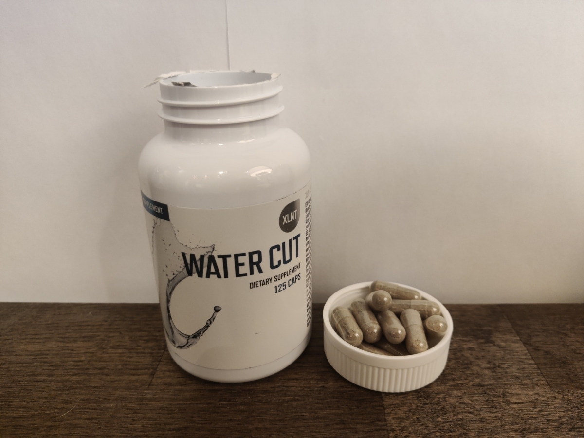 Water Cut med några kapslar i locket på träbord, taget av oss